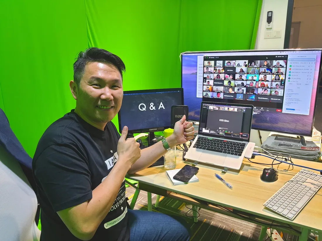 Aaron Chong at his desk, running a live Zoom class with attendees on screen
